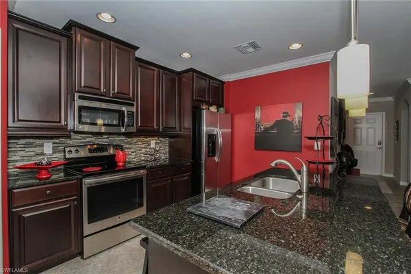 a kitchen with stainless steel appliances granite countertop a stove refrigerator and sink