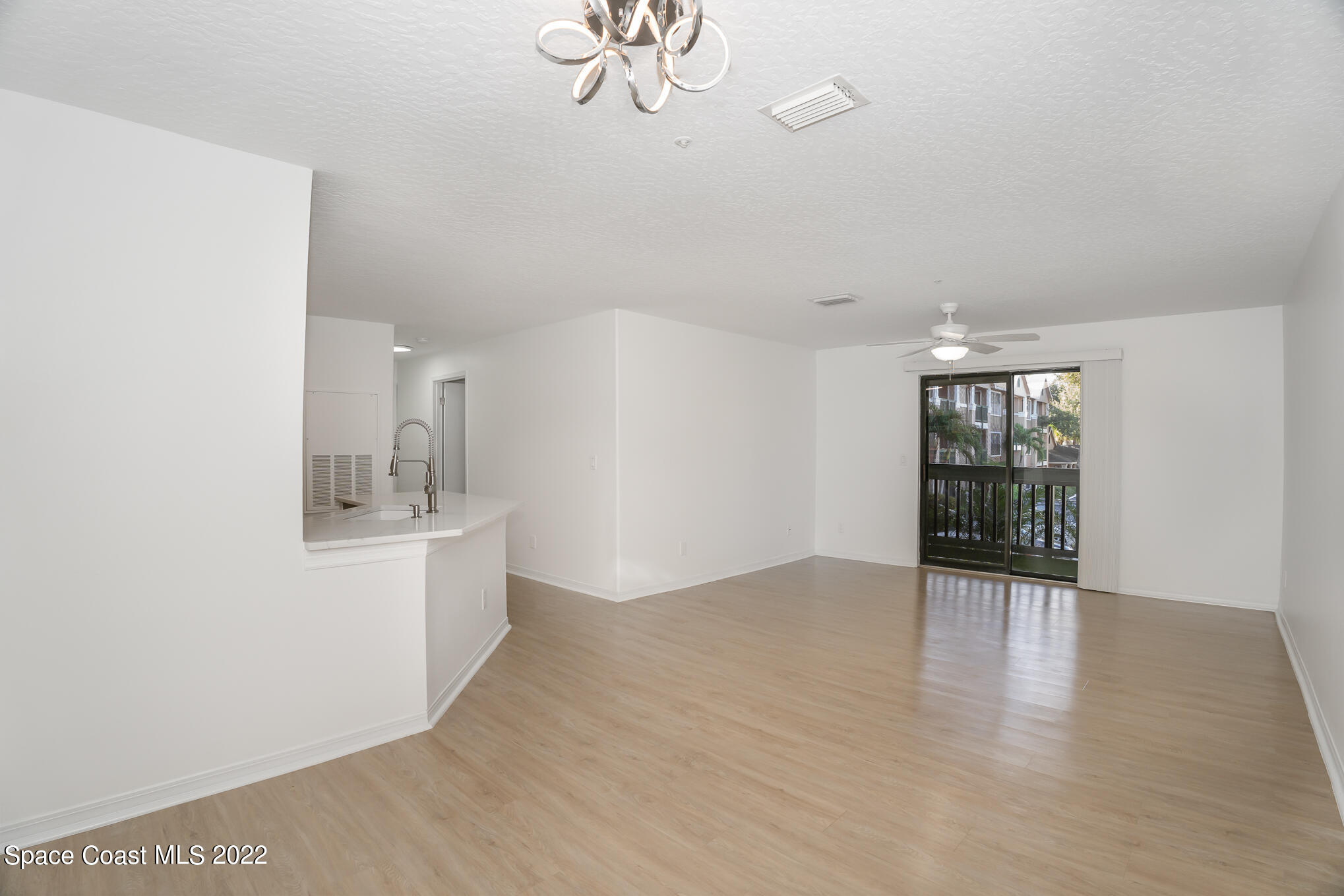 7667 North Wickham Road, Unit 113 Melbourne, FL 32940 - Photo 9 of 29 a view of an empty room with wooden floor and a window
