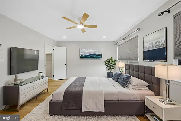 a view of an empty room with wooden floor and a ceiling fan
