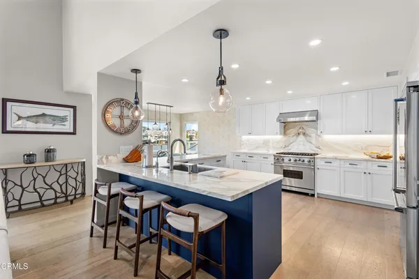 a large kitchen with stainless steel appliances a large counter top a couch and a view of living room