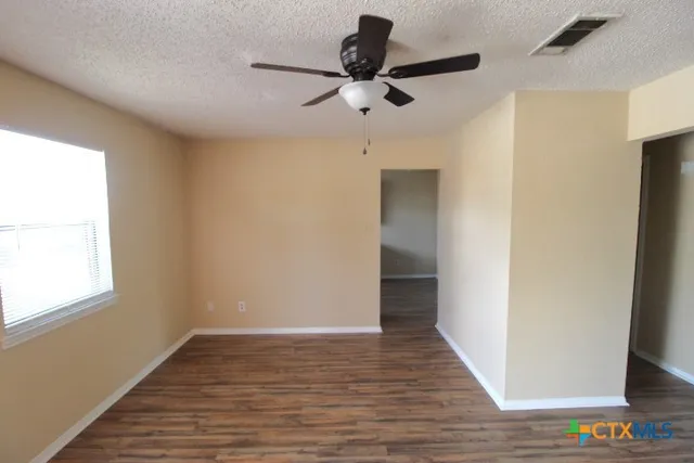 a view of an empty room with wooden floor and a window