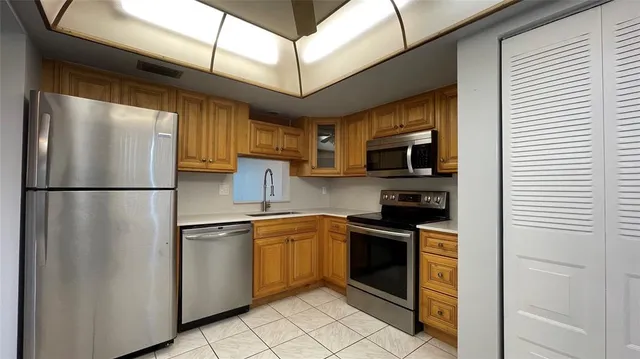 a kitchen with stainless steel appliances granite countertop a refrigerator a stove top oven a sink and dishwasher