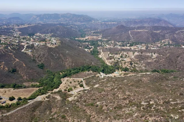 a view of a dry field with mountains in the background
