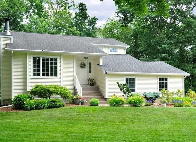 a house that is sitting in front of a big yard with potted plants