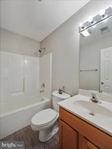 a bathroom with a toilet a sink a mirror a bathtub and vanity