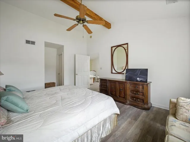 a bedroom with a bed a mirror on dresser and a chandelier