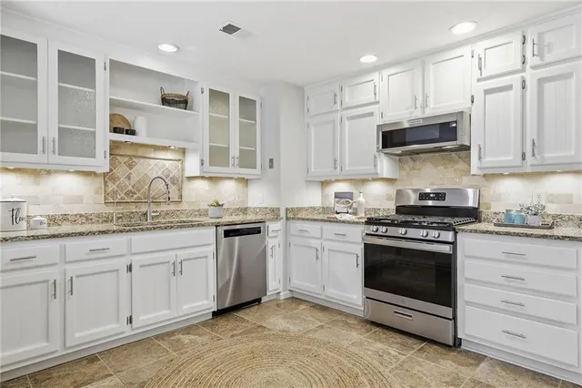 a kitchen with granite countertop white cabinets and stainless steel appliances