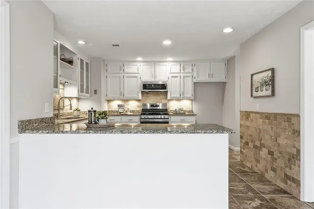 a kitchen with stainless steel appliances granite countertop a sink a stove a refrigerator a microwave and cabinets