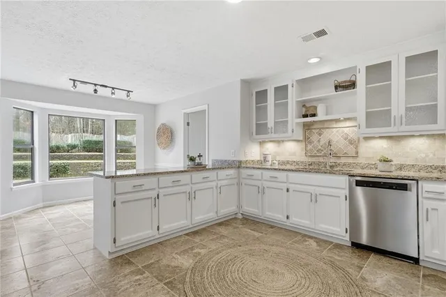 a kitchen with granite countertop a sink and white cabinets