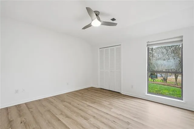 a view of empty room with wooden floor and fan