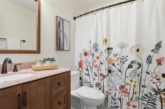 a bathroom with a granite countertop sink a toilet and a mirror
