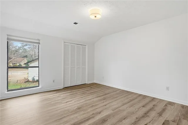 a view of an empty room with window and wooden floor