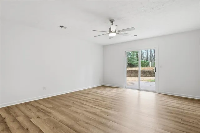 an empty room with wooden floor fan and windows