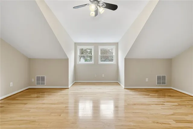 an empty room with wooden floor chandelier fan and windows
