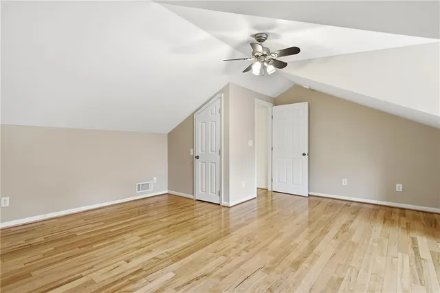 an empty room with wooden floor fan and windows
