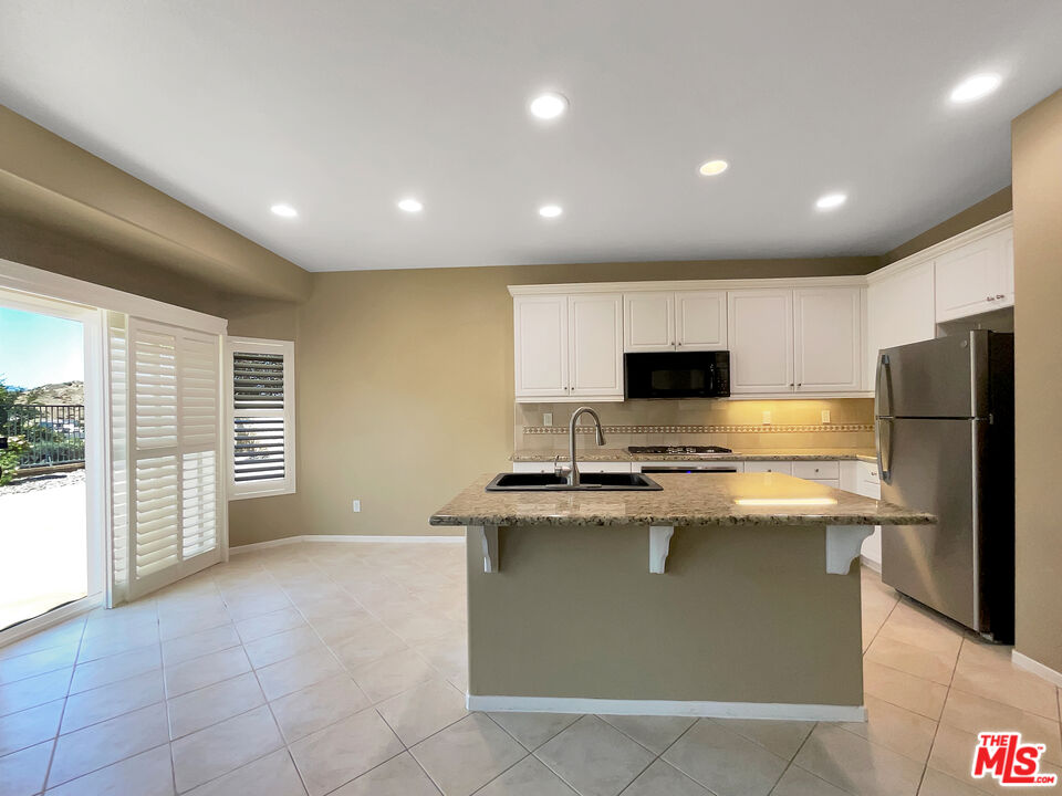 24025 Via Sereno Valencia, CA 91354 - Photo 14 of 27 a kitchen with kitchen island stainless steel appliances a sink stove and refrigerator