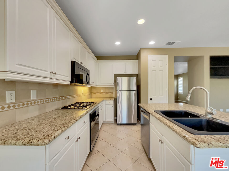 24025 Via Sereno Valencia, CA 91354 - Photo 6 of 27 a kitchen with stainless steel appliances granite countertop a sink stove and refrigerator