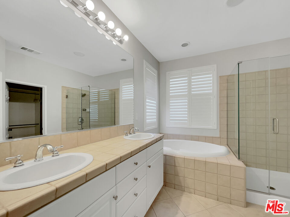 24025 Via Sereno Valencia, CA 91354 - Photo 7 of 27 a spacious bathroom with double vanity a sink a mirror a bathtub and next to a window
