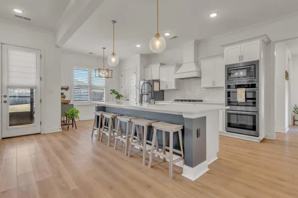 a kitchen with stainless steel appliances granite countertop a stove top oven a refrigerator a sink and a dining table with wooden floor