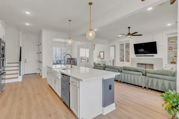 a large kitchen with stainless steel appliances kitchen island granite countertop a sink dishwasher a stove and a dining table with wooden floor