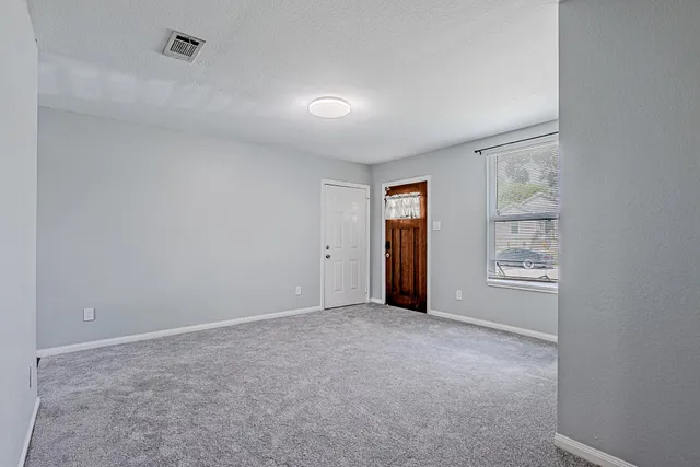 a view of an empty room with window and closet area