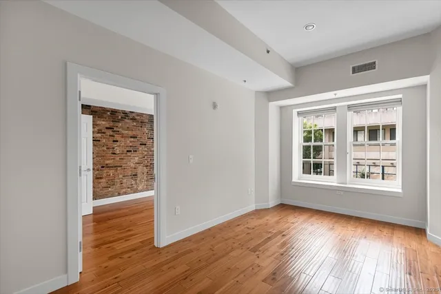 an empty room with wooden floor and windows