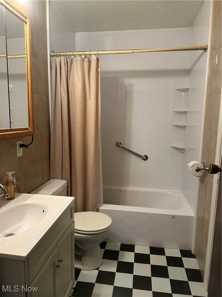 167 Andover Road Woodsfield, OH 43793 - Photo 30 of 50 Full bath featuring tile walls, toilet, shower / bath combo with shower curtain, vanity, and tile patterned floors