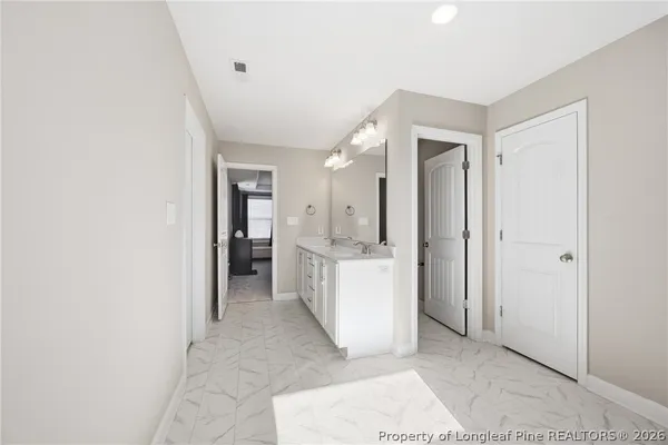 a view of a hallway with bathroom and a sink