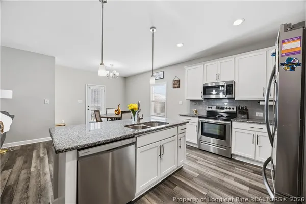 a kitchen with stainless steel appliances granite countertop a sink a stove and refrigerator
