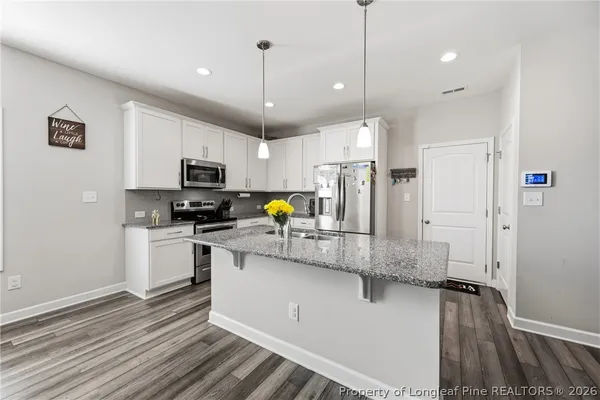 a kitchen with stainless steel appliances a stove a sink a refrigerator a center island and cabinets