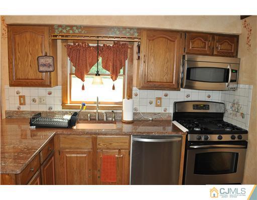 64 Ridge Road Edison, NJ 08817 - Photo 6 of 22 a kitchen with stainless steel appliances wooden cabinets and a stove top oven