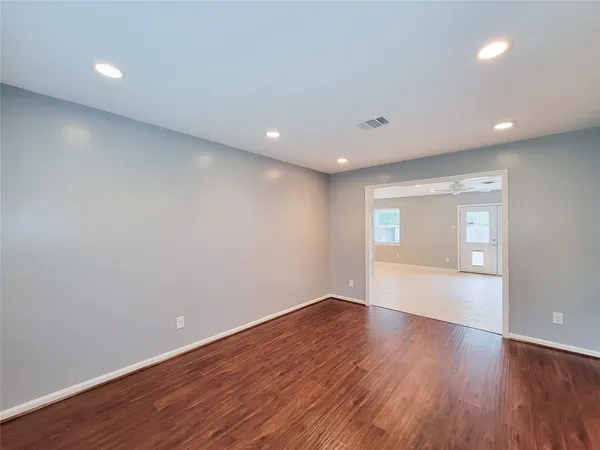a view of an empty room with wooden floor and a window