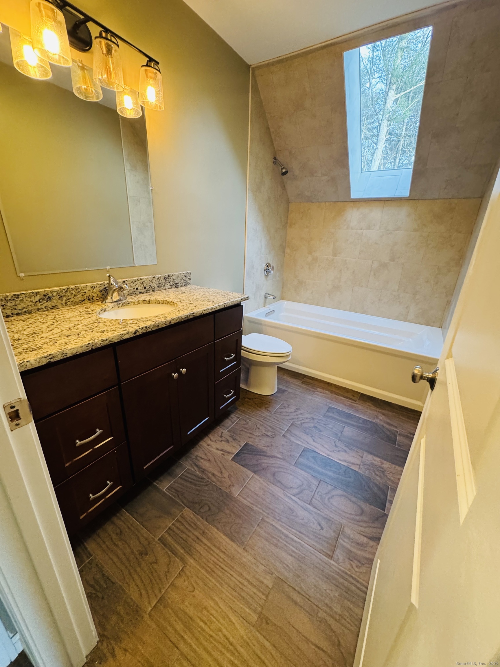 123 Ashford Road, Unit 1 Eastford, CT 06242 - Photo 18 of 24 a bathroom with a granite countertop sink a toilet and bathtub