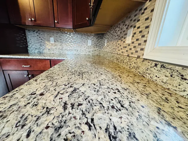 a kitchen with granite countertop white cabinets and wooden floor