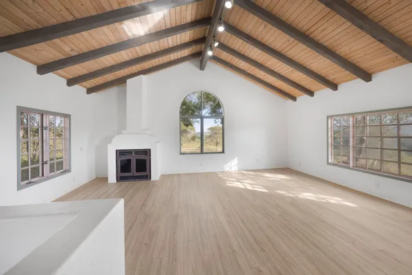 a view of a livingroom with wooden floor a ceiling fan and windows