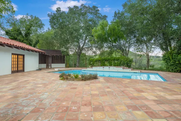 a view of backyard with swimming pool and green space
