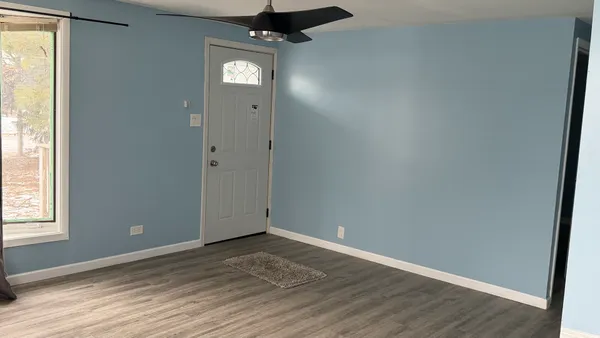an empty room with wooden floor cabinet and windows