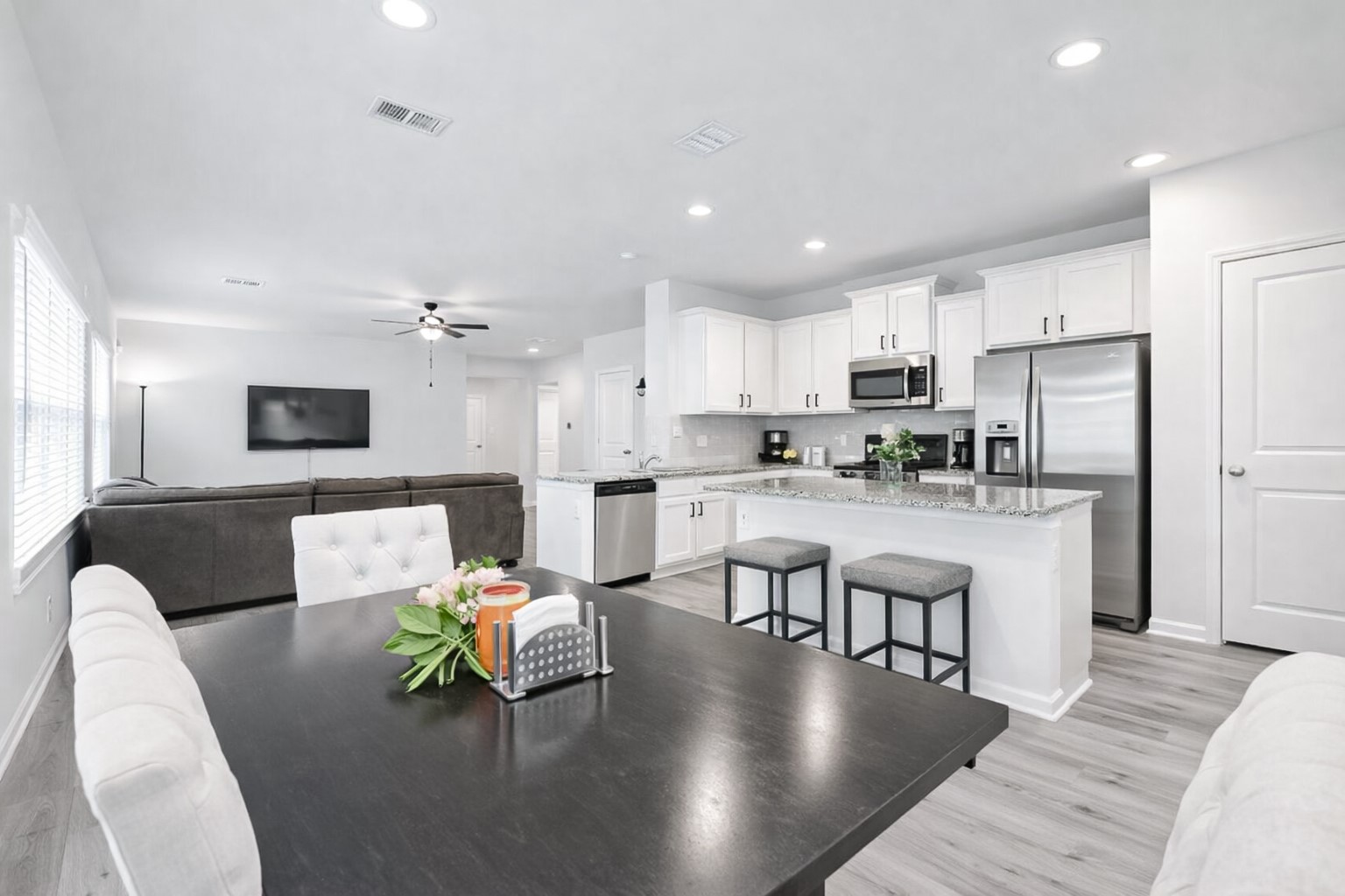 940 Paddock Lane Georgetown, TX 78626 - Photo 12 of 32 Open-concept living space featuring a kitchen with white cabinetry, stainless steel appliances, and a granite-finish island