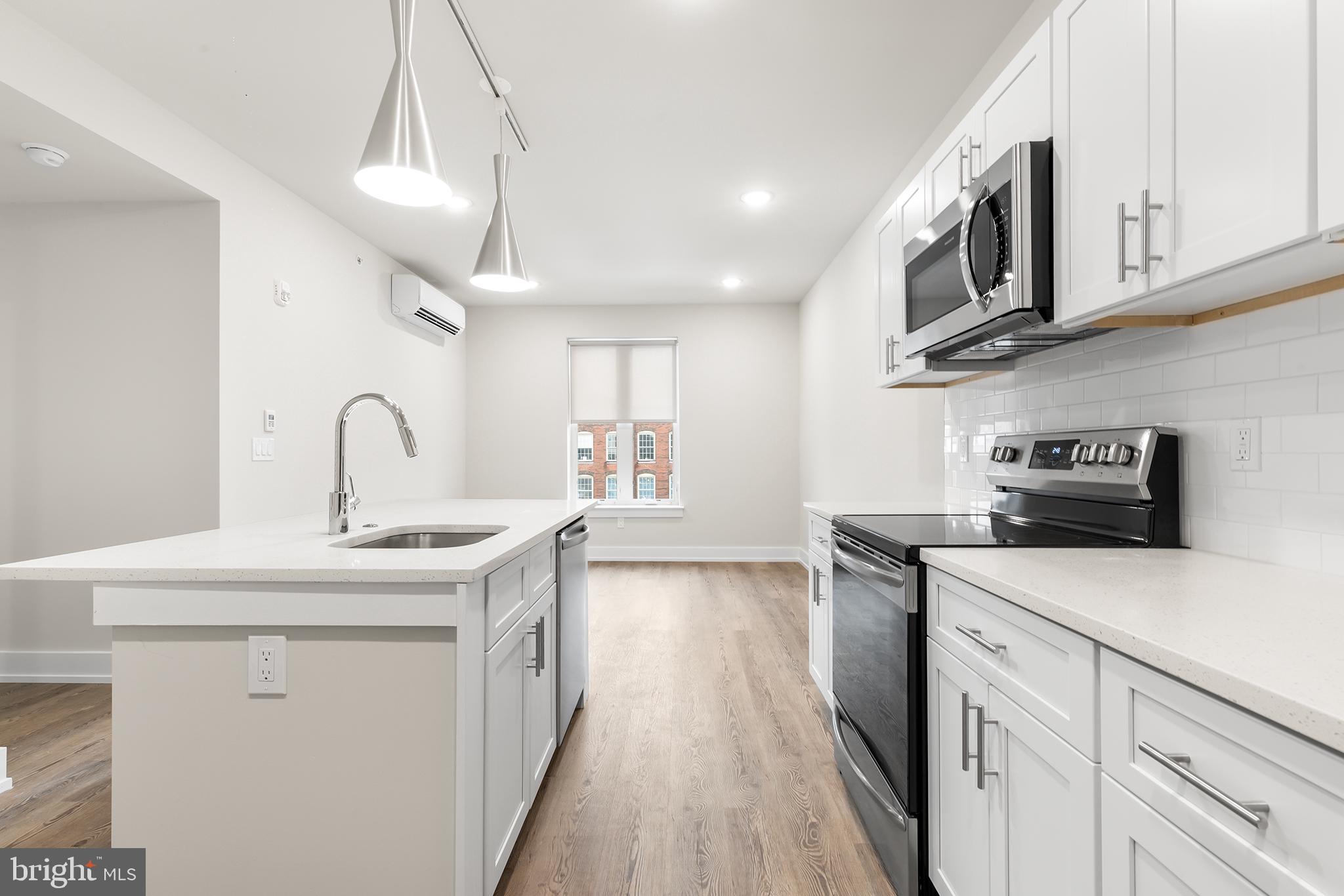 214 Vine Street, Unit 604 Philadelphia, PA 19106 - Photo 21 of 35 a kitchen with stainless steel appliances granite countertop a sink and dishwasher a stove top oven with wooden floor