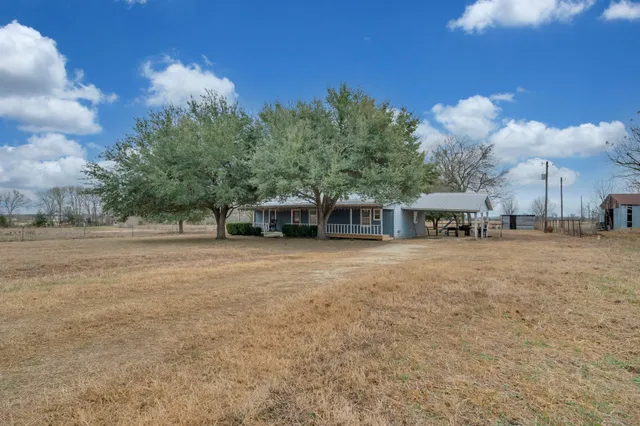 a view of a house with backyard and trees