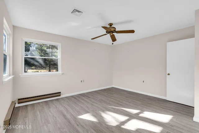 a view of empty room with wooden floor and fan