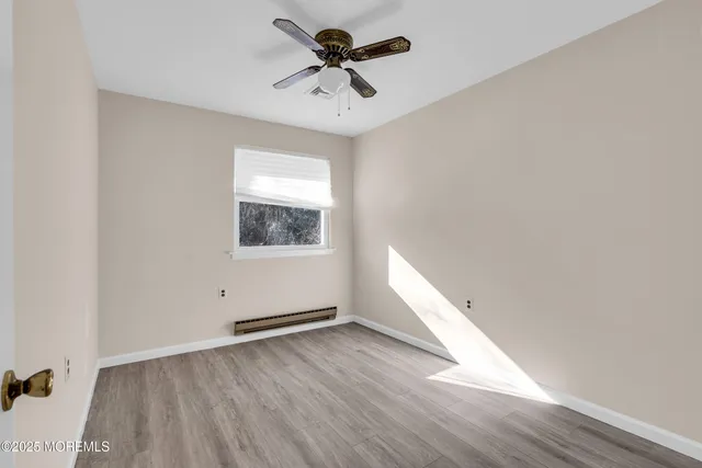 an empty room with wooden floor chandelier fan and windows
