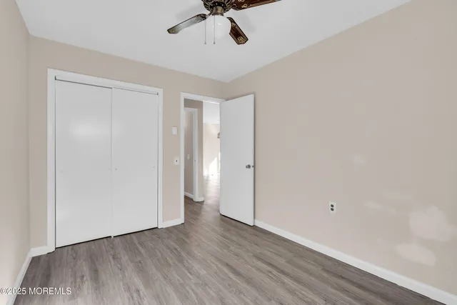 a view of a room with wooden floor and ceiling fan