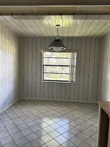a view of an empty room with window and chandelier fan