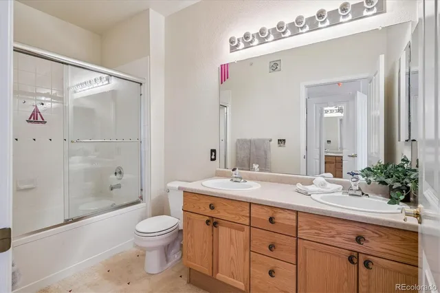 a bathroom with a granite countertop sink a toilet and shower