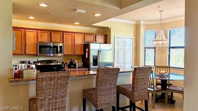 a dining room with stainless steel appliances granite countertop furniture a flat screen tv and a large window