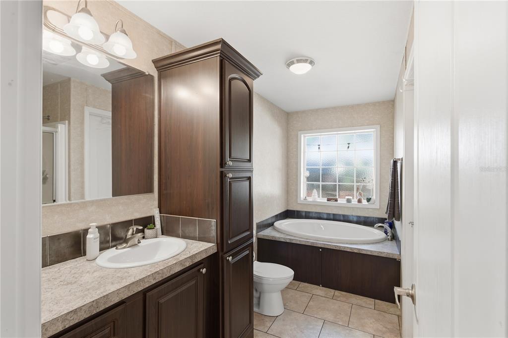 4506 Northwest 10th Street Bell, FL 32619 - Photo 45 of 50 a bathroom with a granite countertop sink mirror bathtub and toilet