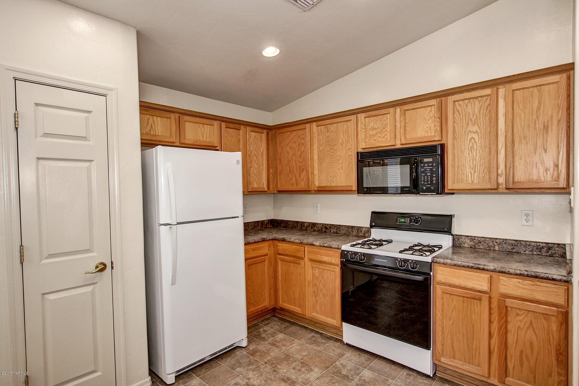 8350 East Bowline Road Tucson, AZ 85710 - Photo 5 of 26 a kitchen with white cabinets and white appliances