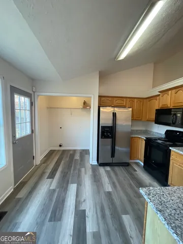 a view of a kitchen with wooden floor and electronic appliances