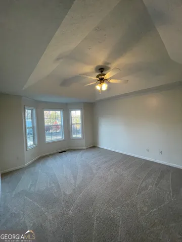 an empty room with windows and chandelier fan